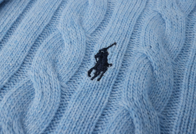 Close-up of a blue knitted fabric with a small logo on it.