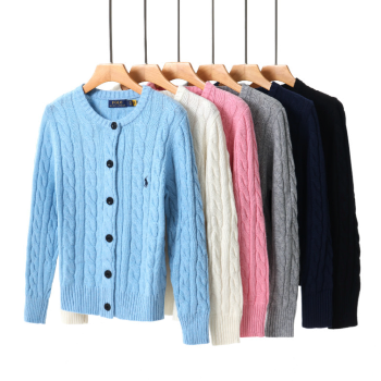 Row of colorful cable knit cardigans on hangers against a white background