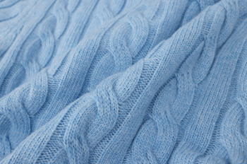 Close-up of a blue knitted fabric with cable pattern