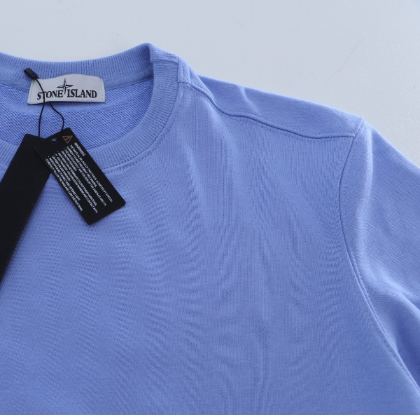 Light blue sweater with Stone Island tag on a light gray background