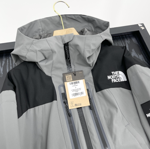 Hooded outdoor jacket in black and grey hanging on hangers