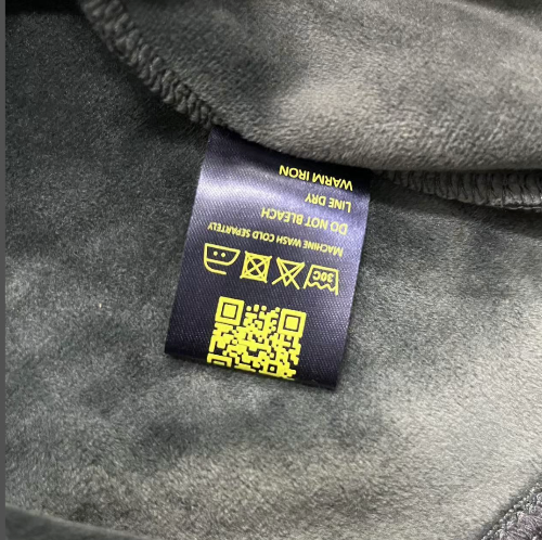 Clothing label with QR code on a gray fabric background