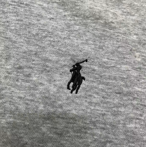 Close-up of a gray fabric with a black embroidered logo.