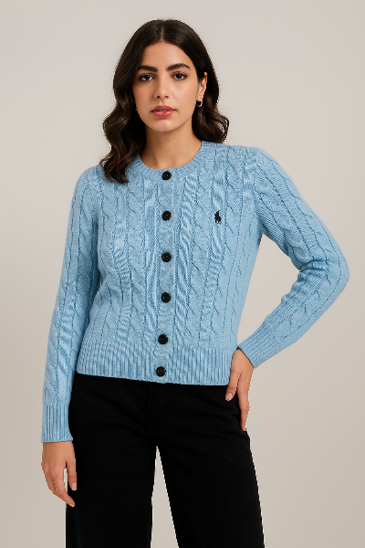 Woman wearing a light blue cable knit cardigan with black buttons on a neutral background