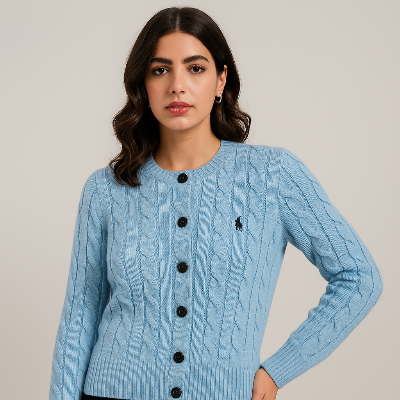 Woman wearing a light blue cable knit cardigan with black buttons on a beige background