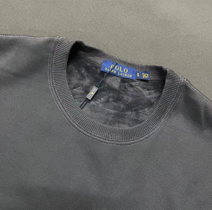 Close-up of a gray sweater with a Polo Ralph Lauren tag on a gray background